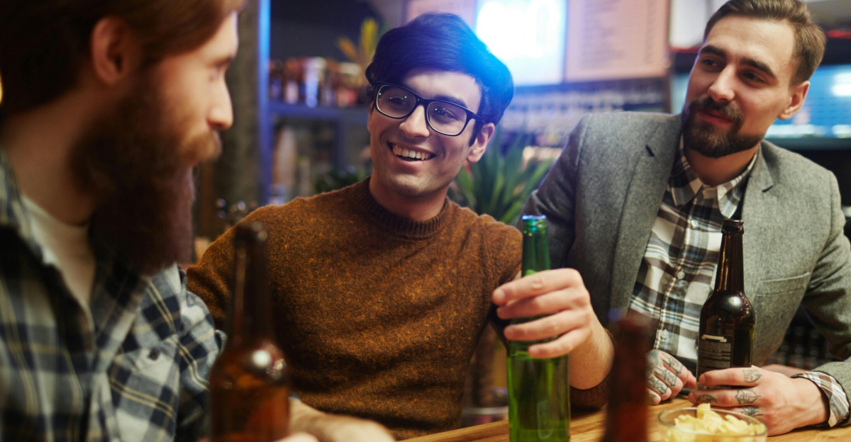 Three men smiling and enjoying beer together indoors. Perfect for themes of friendship and leisure.