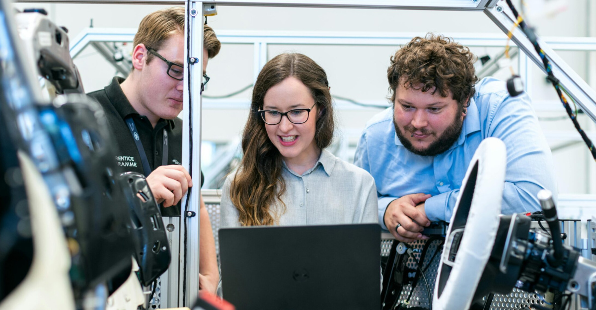 Engineers collaborating on a car project in a modern automotive workshop using advanced technology.