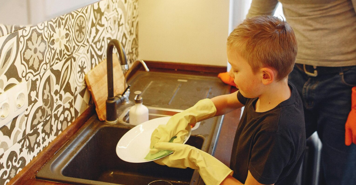 A boy and his father washing dishes, promoting family bonding and teamwork at a kitchen sink.