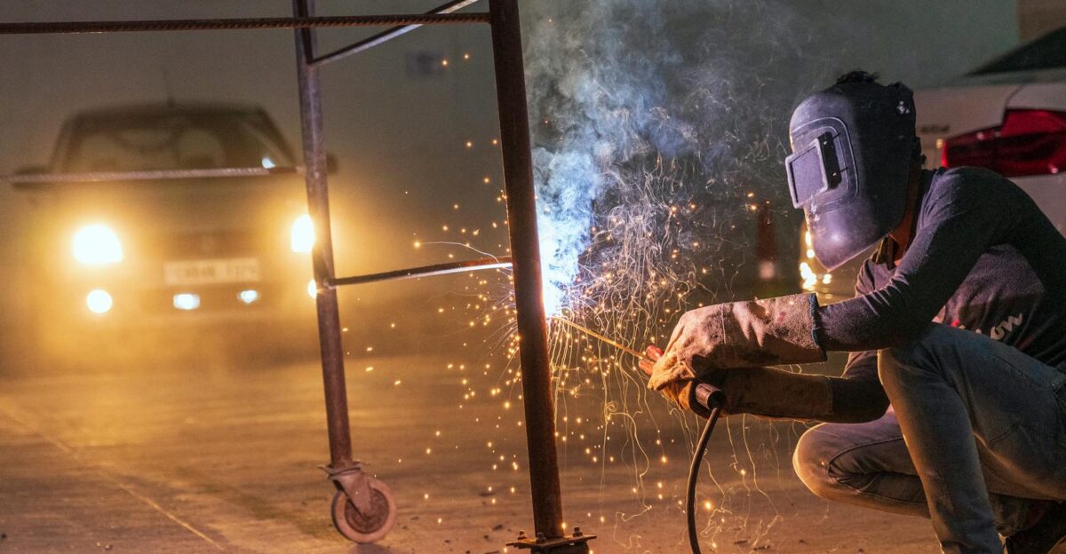 A welder at work with sparks flying in an industrial setting during night time