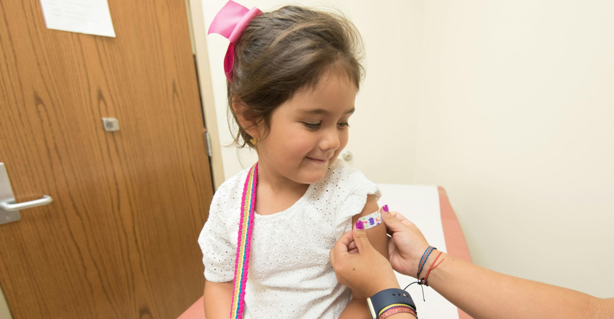 A cheerful young girl receives a band-aid after a vaccination at a clinic.