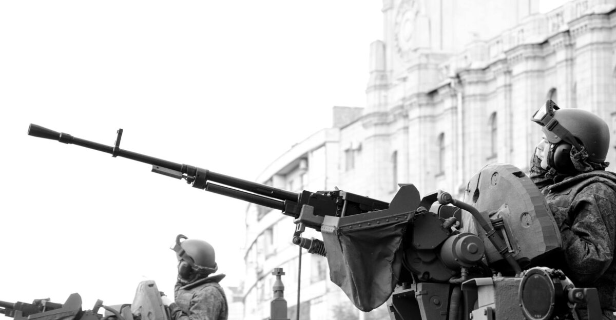 Monochrome image of soldiers in armored tanks equipped with rifles patrolling urban surroundings
