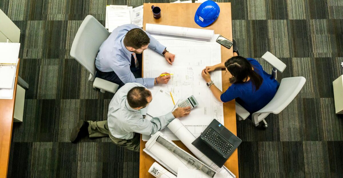 Top view of a team working on construction plans in an office setting