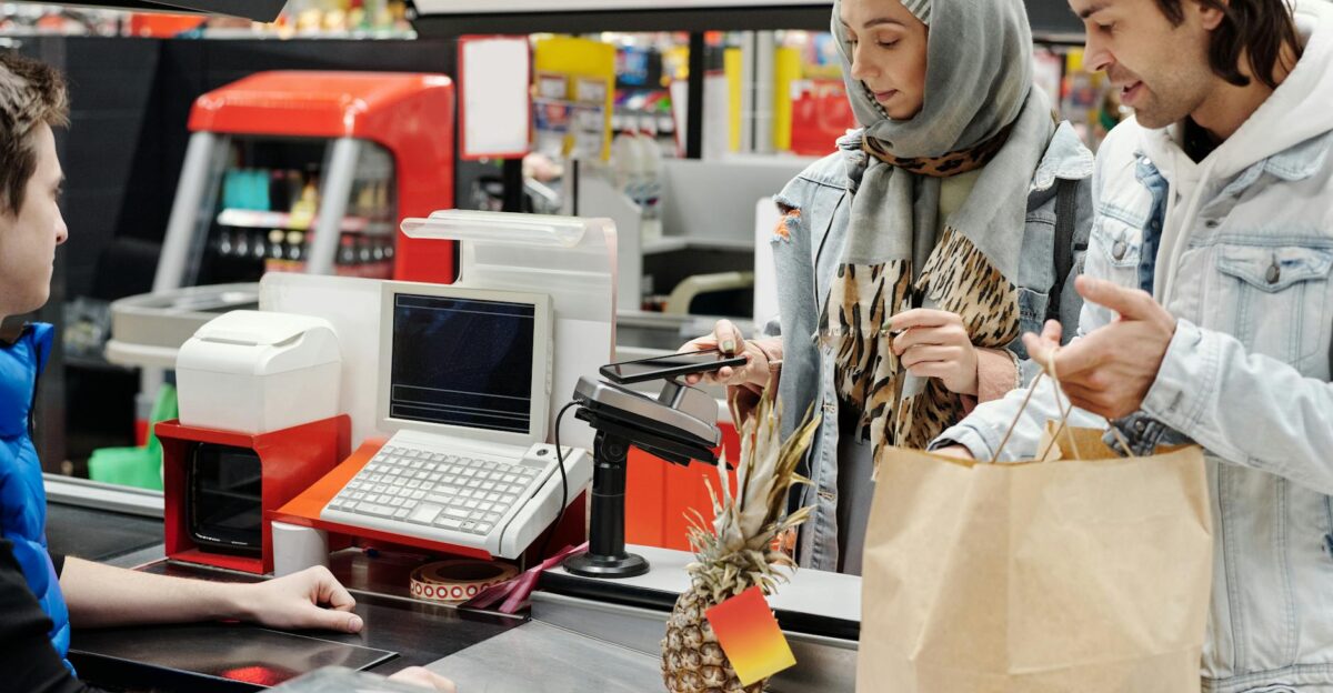 A couple in a supermarket checkout using mobile payment with a cashier Modern retail technology