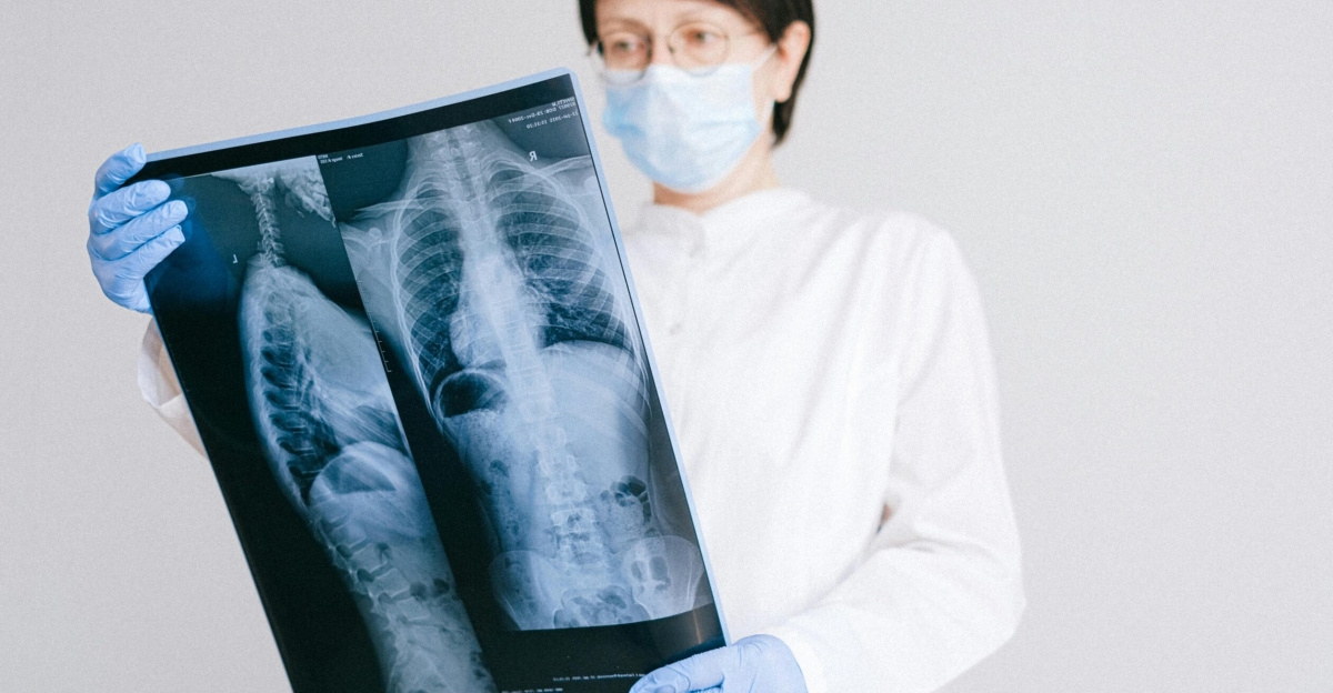 Doctor reviewing X-ray wearing protective gear in hospital setting.