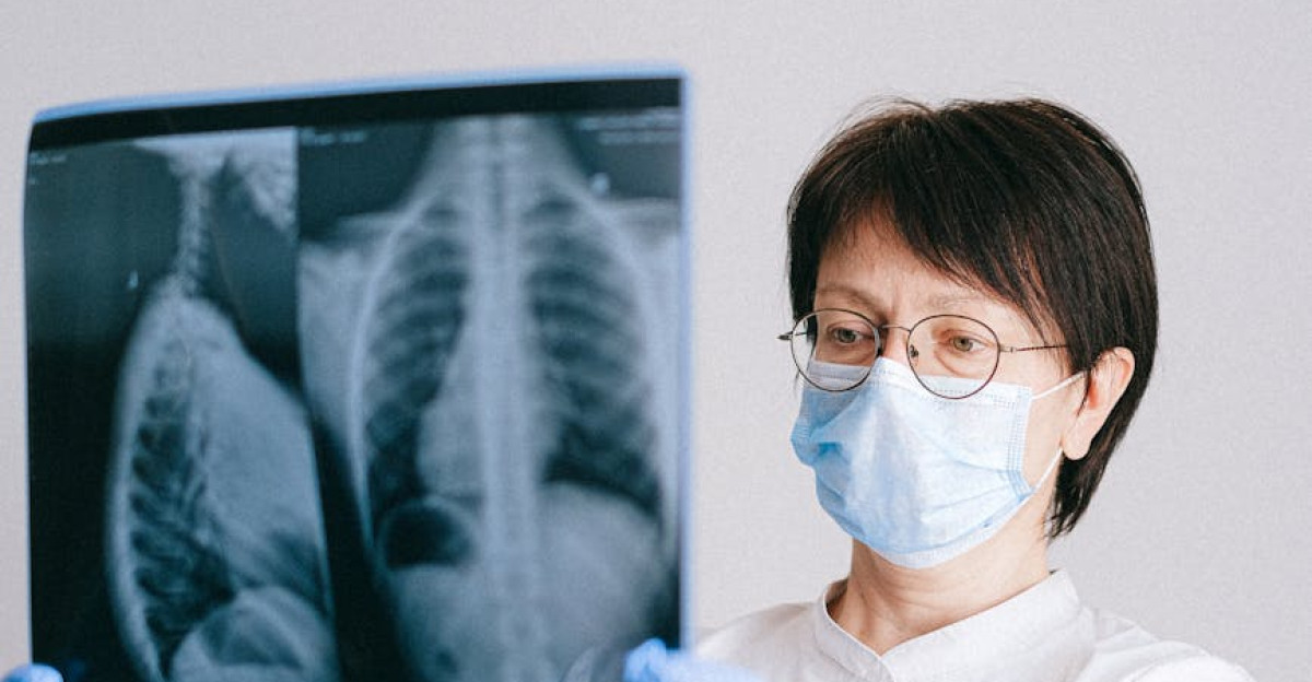 Medical professional in PPE examining chest X-ray results for diagnosis
