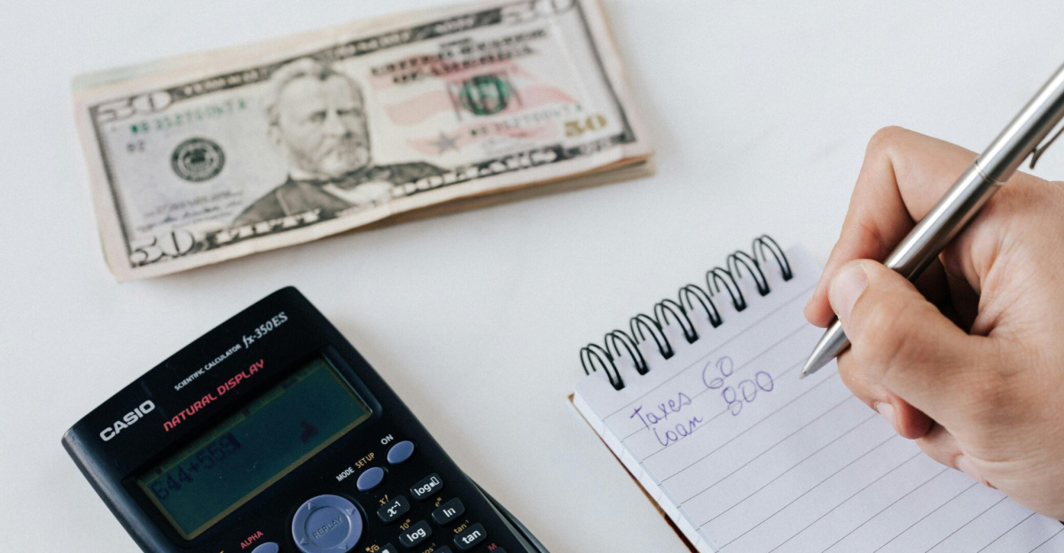 Close-up of budgeting items including calculator, cash, and notebook for financial planning.