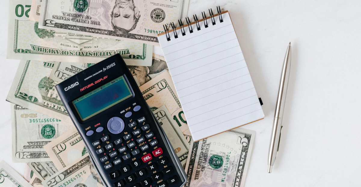 Flat lay of US dollar bills with calculator and notebook for budgeting.