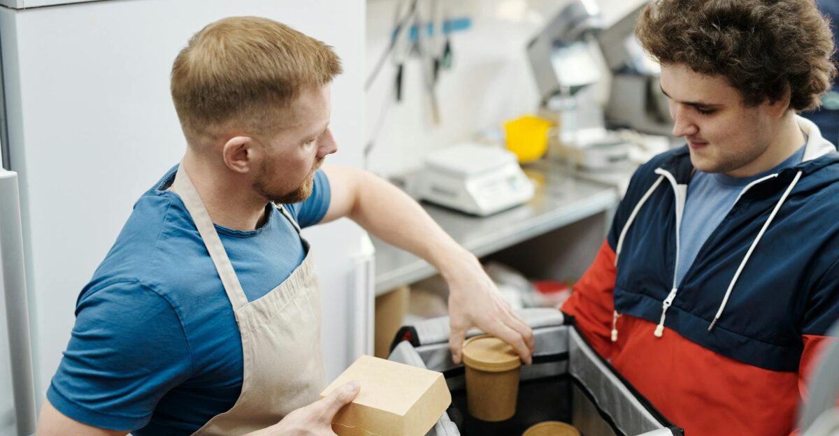 Two young men preparing food delivery orders in a small business kitchen