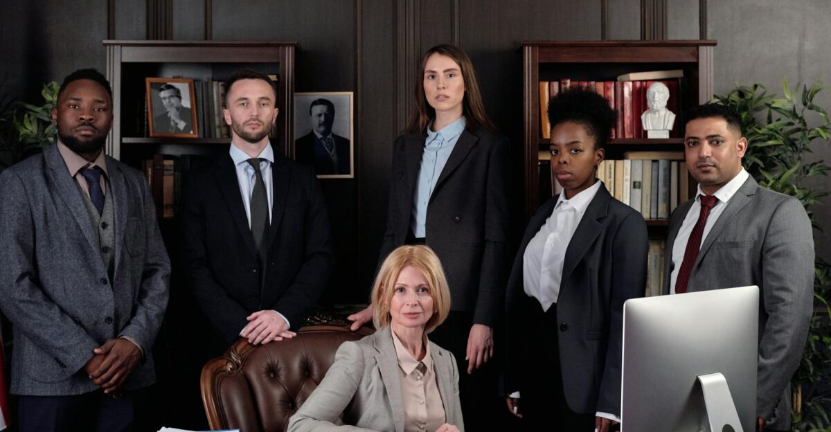 Diverse group of professionals in corporate attire posing confidently in an office environment