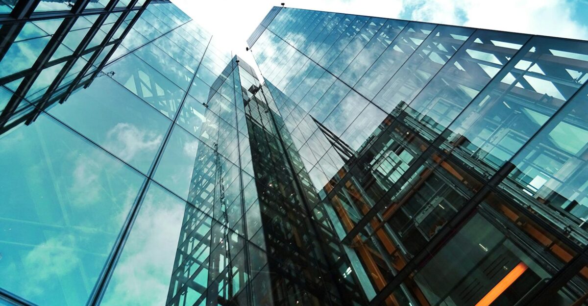 A striking view of a modern glass skyscraper reflecting the sky and clouds