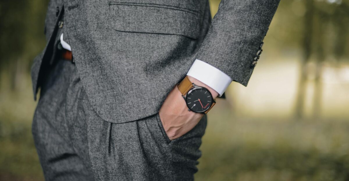 Close-up of a man in a tailored suit wearing an elegant wristwatch outdoors exuding fashion and sophistication