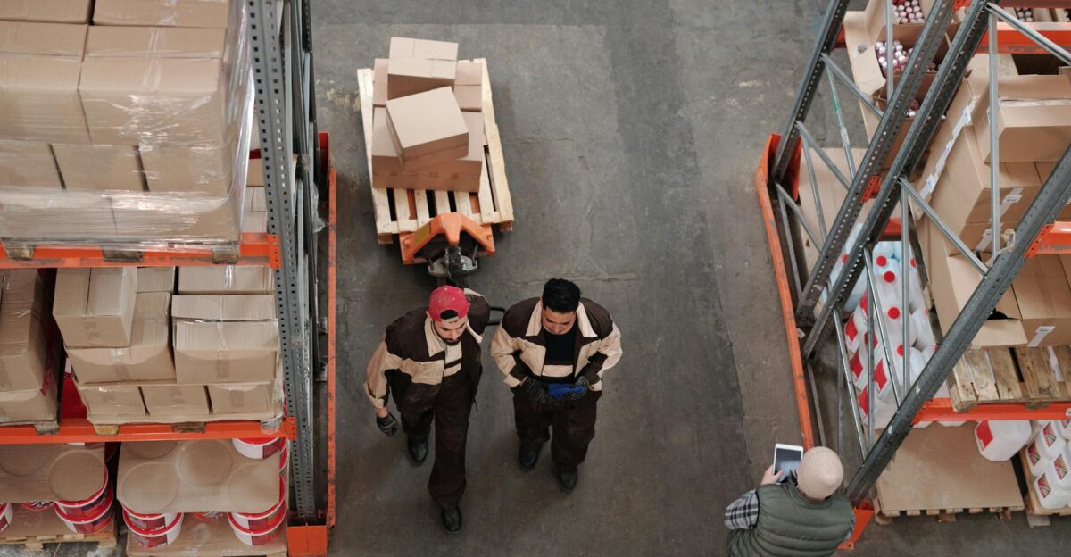 High angle view of warehouse workers organizing and preparing shipments with boxes and pallets