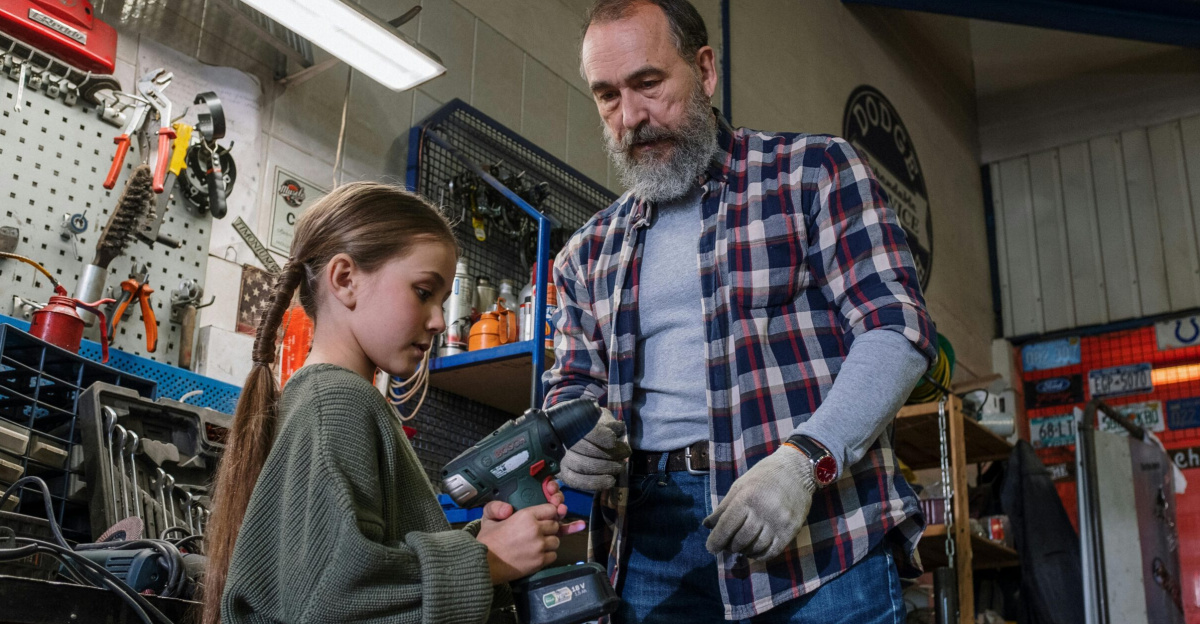 Father and daughter share bonding time in an auto workshop, using power tools.