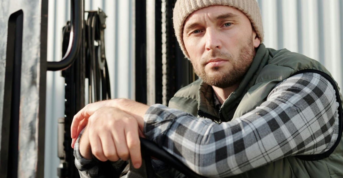 Adult male forklift operator in casual wear working outdoors. Sunlit environment.