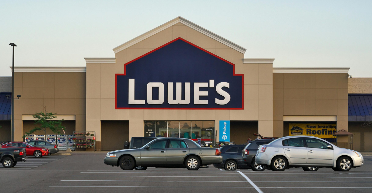 Front view of a Lowe's store entrance with parked cars in the lot during the day.