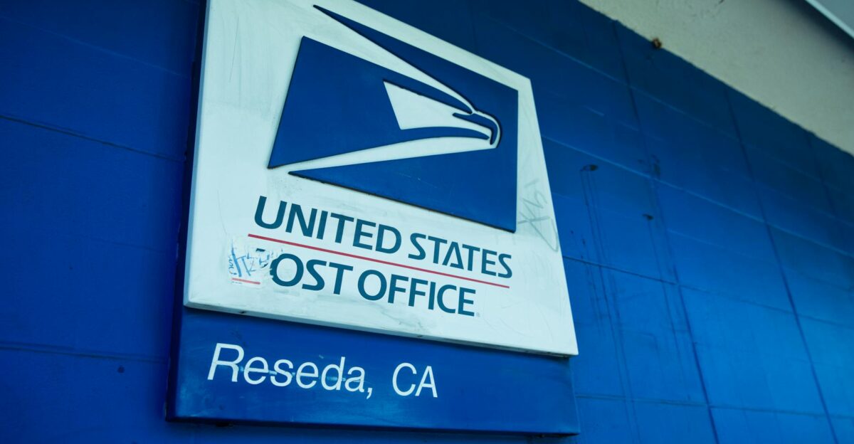 Close-up of the United States Post Office sign against a blue wall in Reseda CA