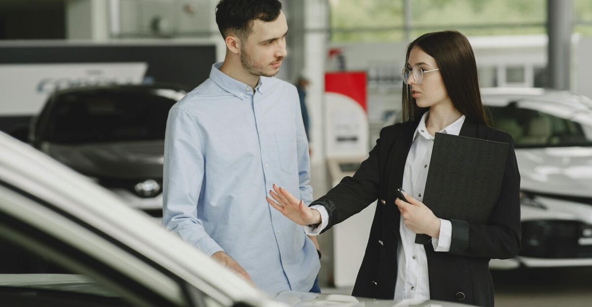 A salesperson and customer discussing car features in a dealership setting
