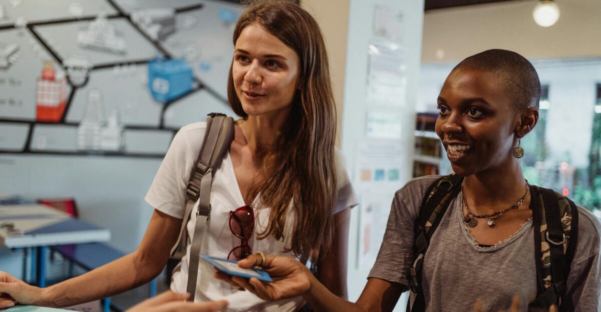 Two women tourists engaging at a hostel reception offering a friendly atmosphere