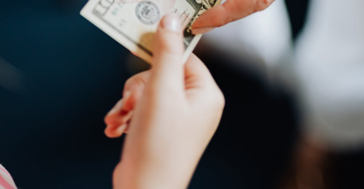 Close-up of hands exchanging a US dollar bill emphasizing financial transactions