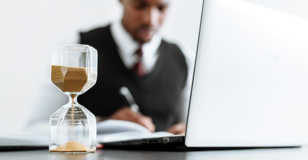 Businessman at desk with hourglass indicating time management and daily work routine