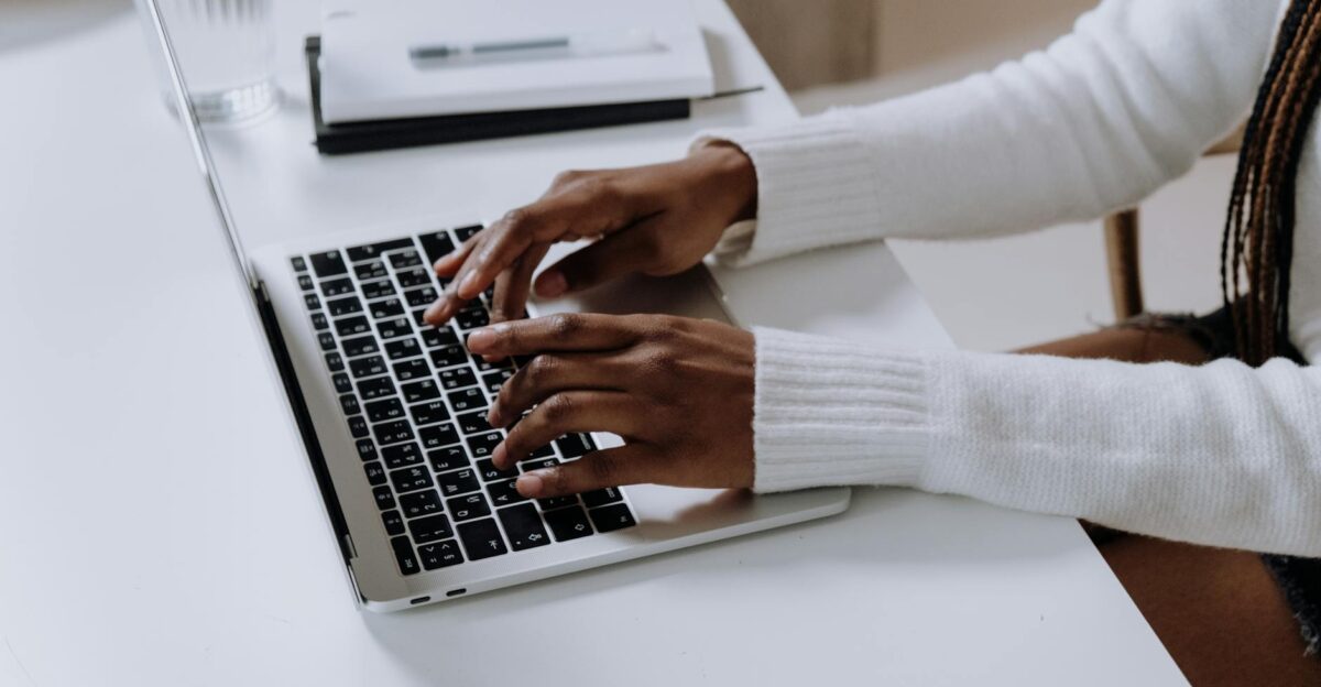 Close-up of woman s hands typing on a laptop in a modern home office setting