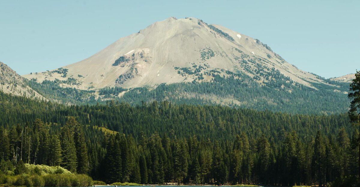 Stunning view of Lassen Peak and Manzanita Lake surrounded by lush forest in summer