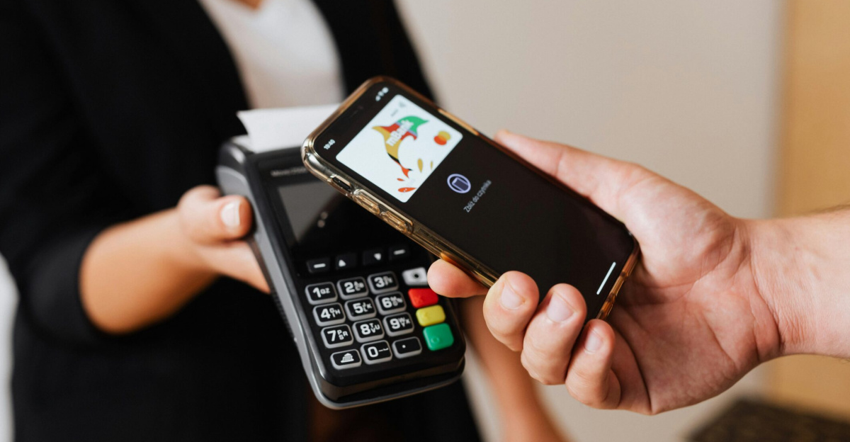 A person using a smartphone for contactless payment at a retail store counter.