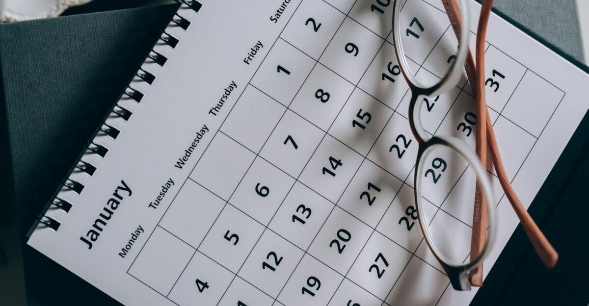 A close-up of a January calendar with eyeglasses on a table emphasizing planning and organization
