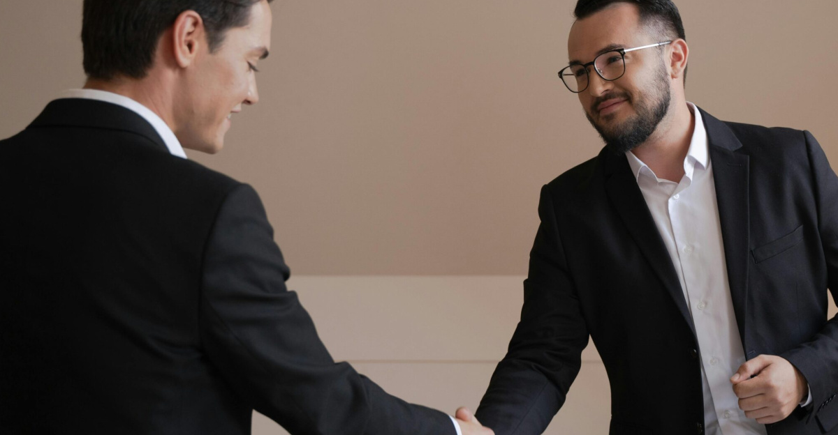 Two businessmen shaking hands in an office, symbolizing agreement and cooperation.