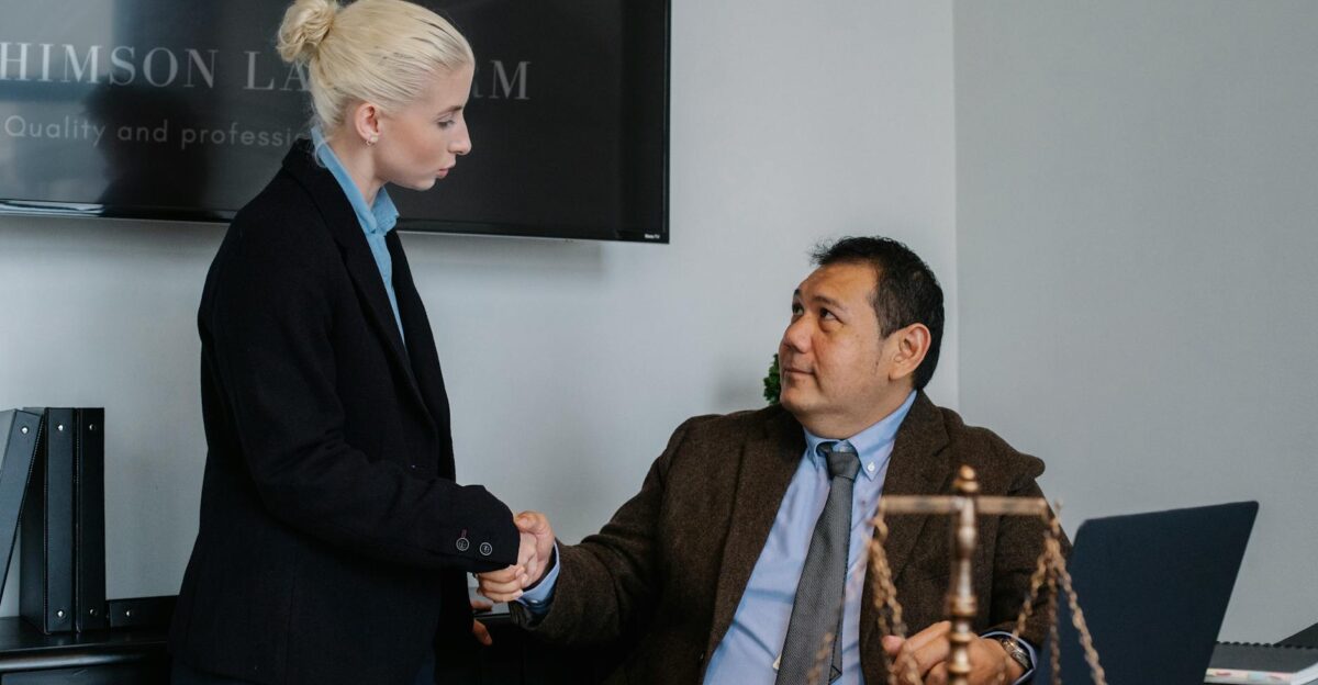 A male and female professional shaking hands in a law office environment
