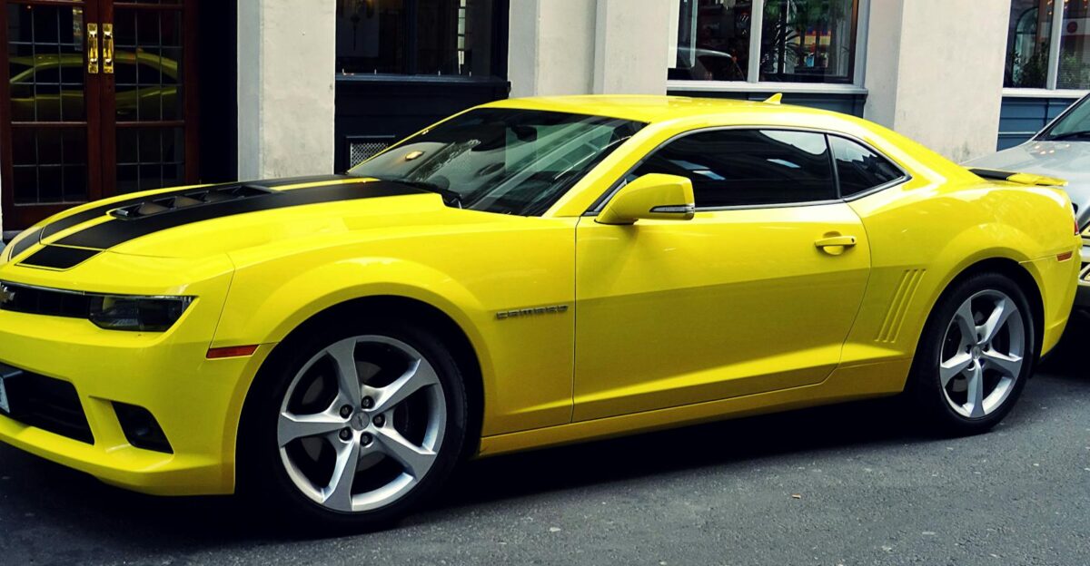 A stylish yellow Chevrolet Camaro parked on a city street showcasing its sporty design