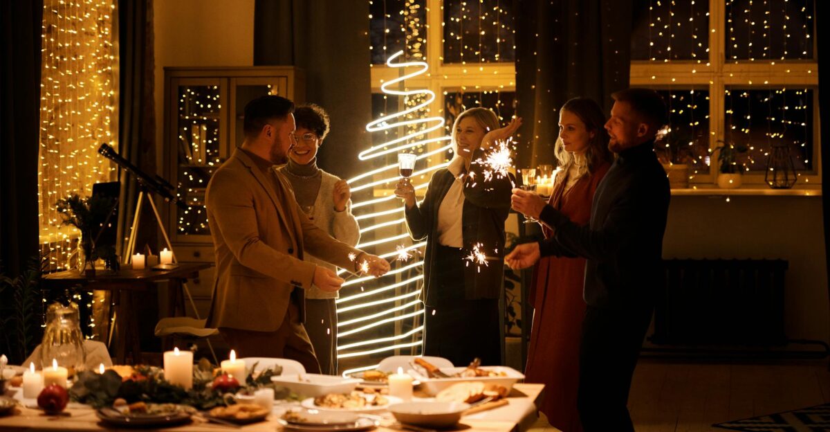 Group of adults celebrating Christmas indoors with sparklers and festive decor