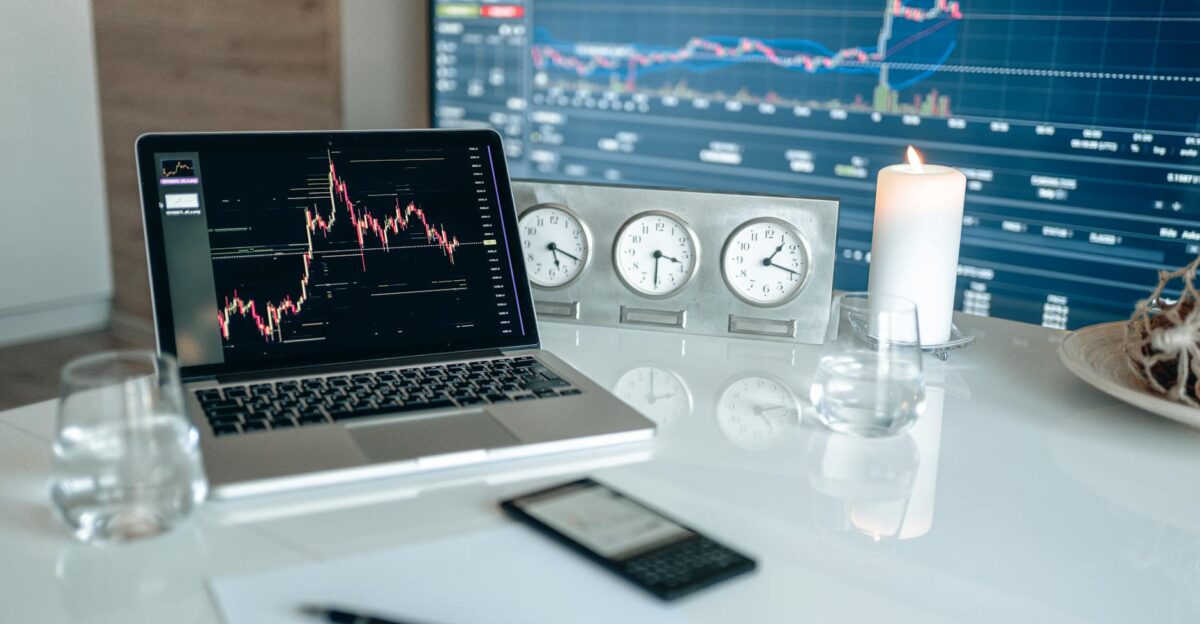 A modern workspace featuring financial charts and multiple clocks on a white table ideal for trading