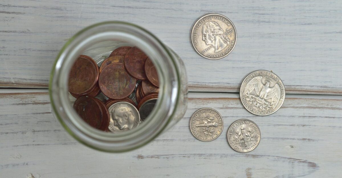 Top view of a jar filled with coins placed on a wooden table depicting savings