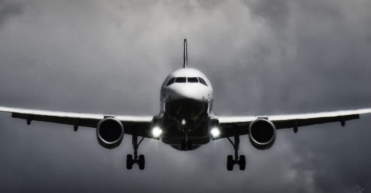 A dramatic view of an airplane landing with stormy clouds overhead, showcasing aviation in a monochrome scene.