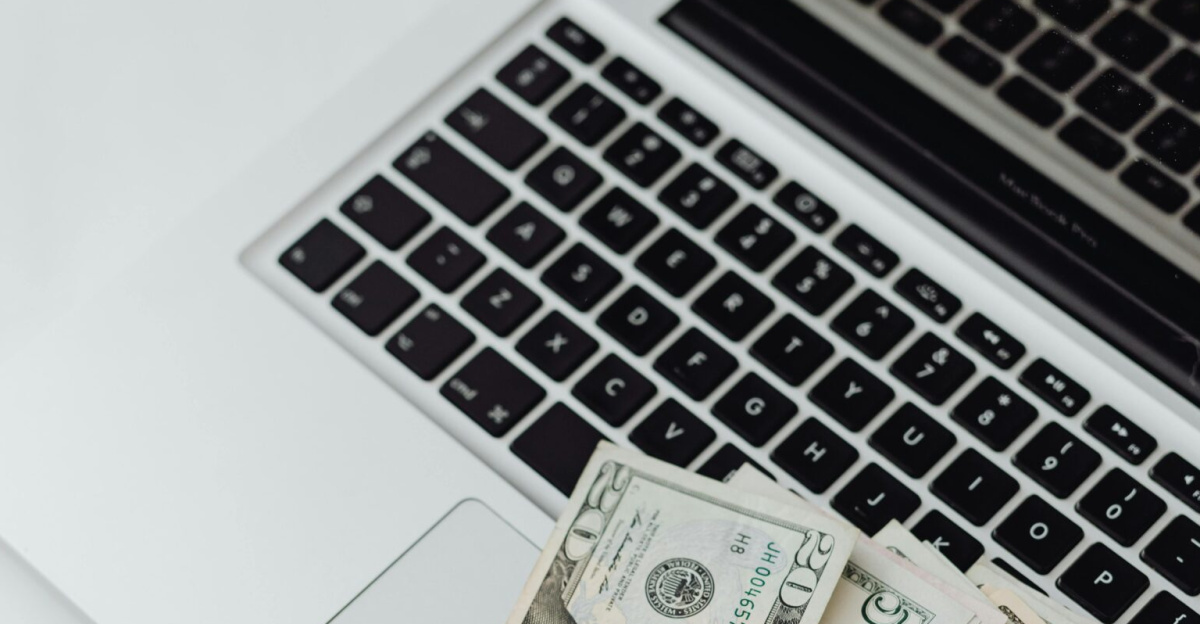 A stack of US dollar bills on a laptop keyboard representing online finance and budgeting.