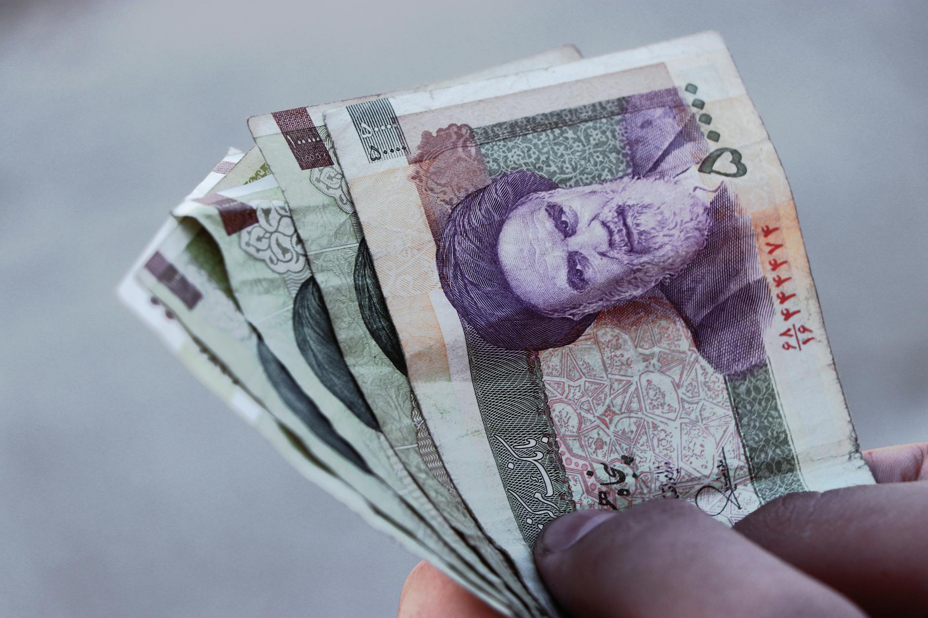 Detailed view of Iranian rial banknotes held in hand illustrating finance and economy in Iran