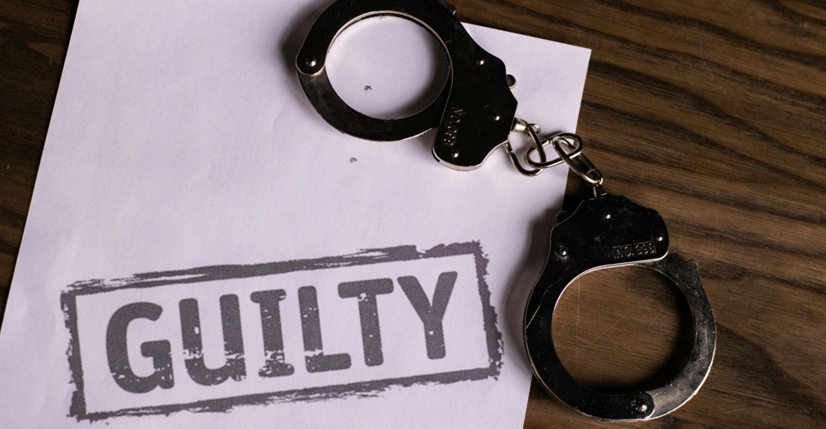 Top view of handcuffs on paper with 'GUILTY' text, symbolizing a verdict or crime.