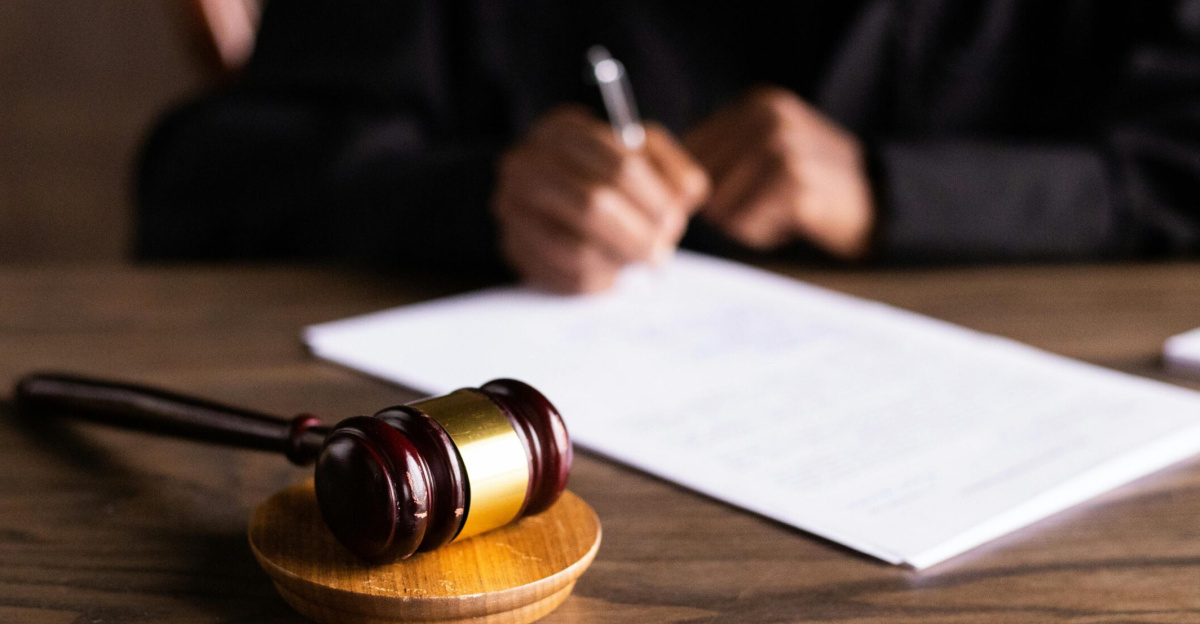 Judge signing documents at desk with focus on gavel, representing law and justice.