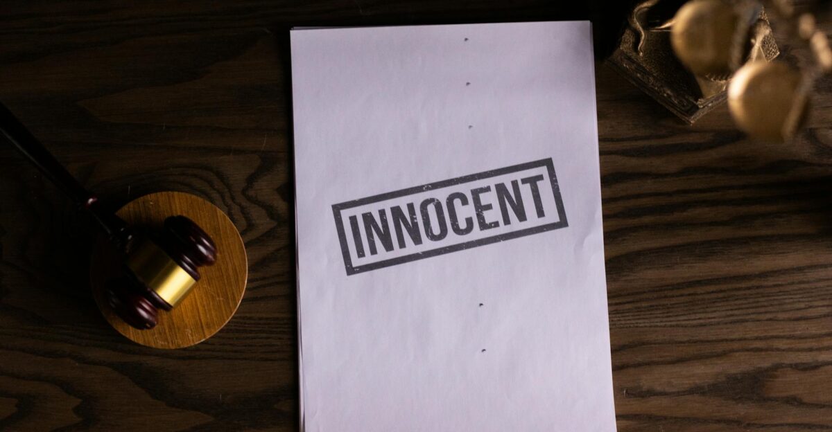 Close-up of legal document stamped Innocent beside a gavel on a wooden desk