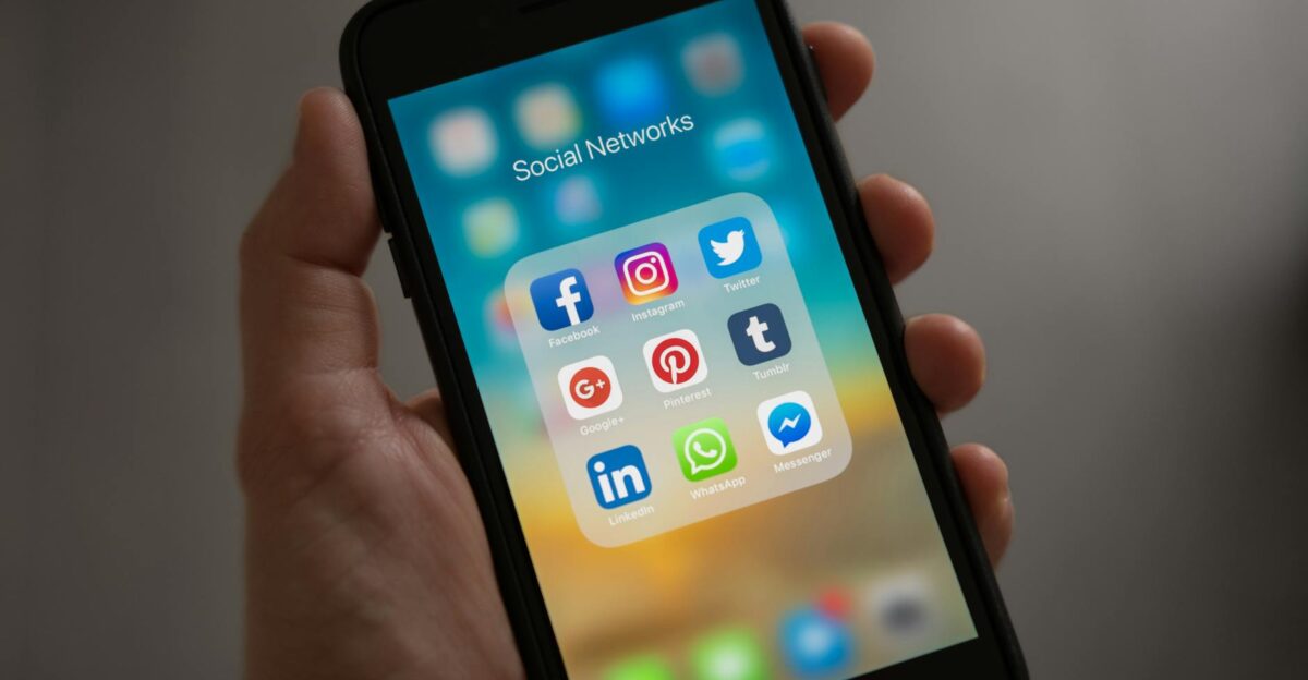 A smartphone displaying various social media icons held in a hand showcasing modern communication apps