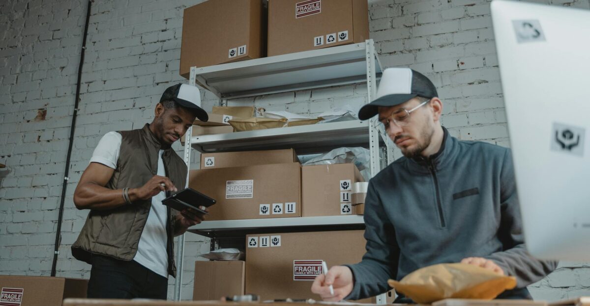 Two warehouse employees organizing and packing parcels for delivery in a modern indoor setting