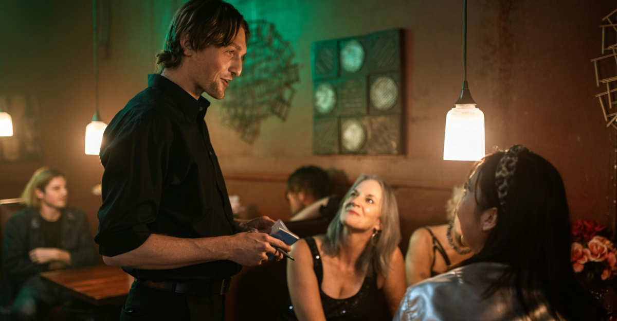 A waiter serves customers in a warmly lit restaurant with modern interior design.