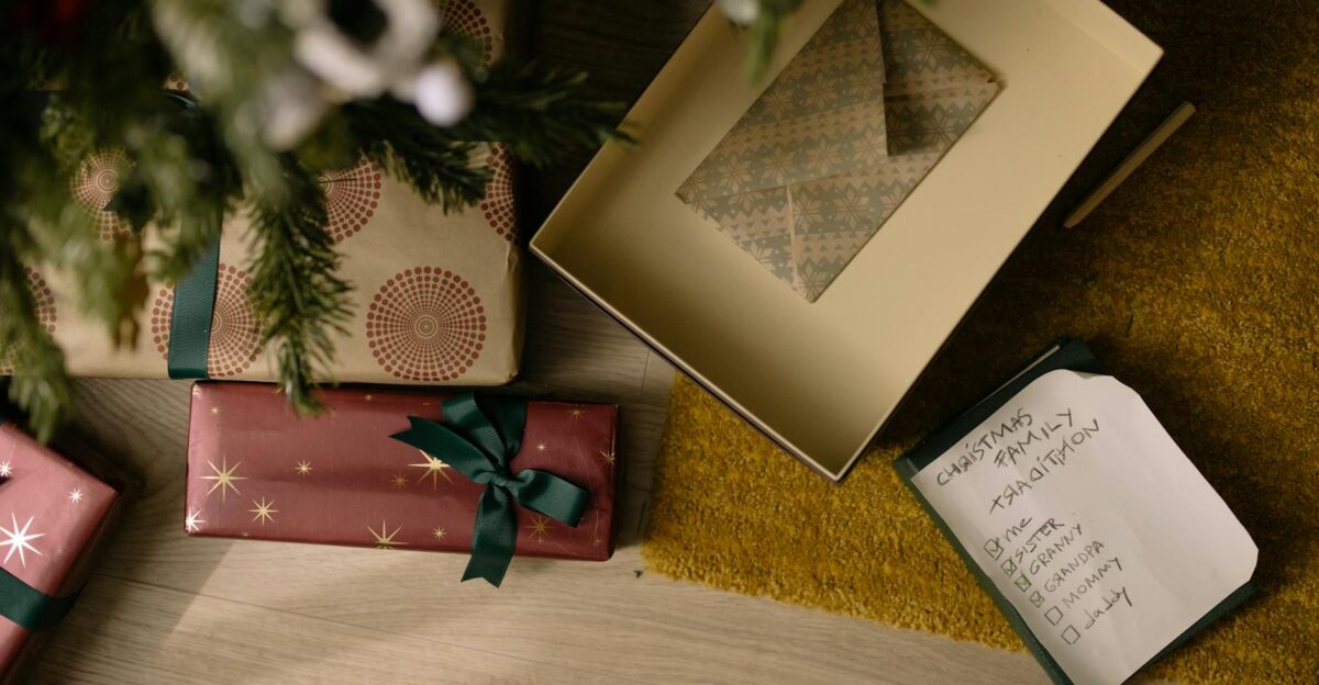 Top view of wrapped Christmas gifts and family checklist under a tree