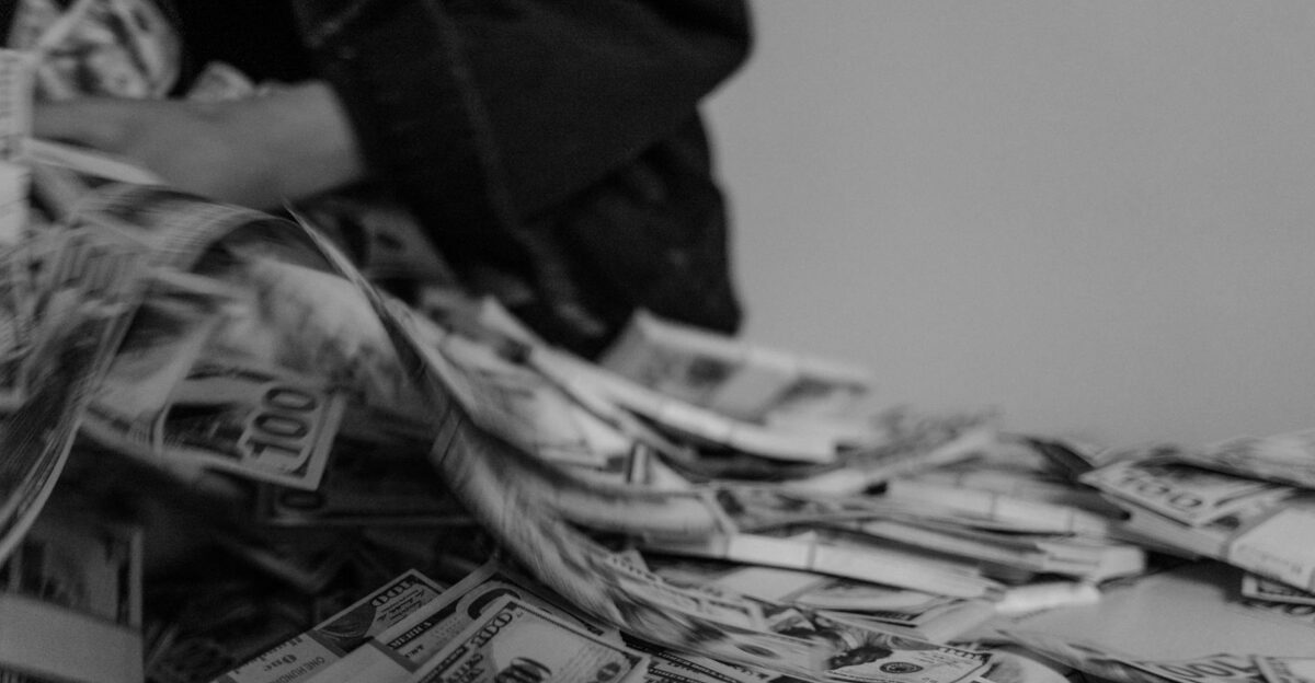 A blur of hands moving through a pile of US dollar bills captured in black and white