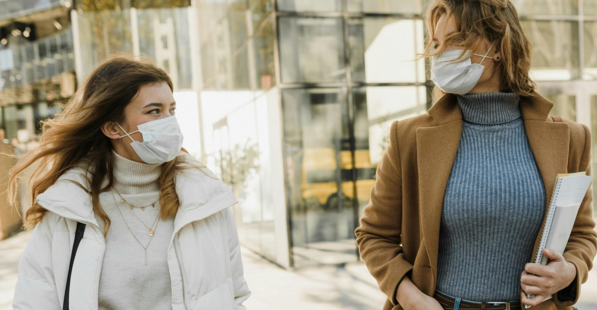 Two women wearing masks walking outdoors on a sunny day, embracing the new normal.