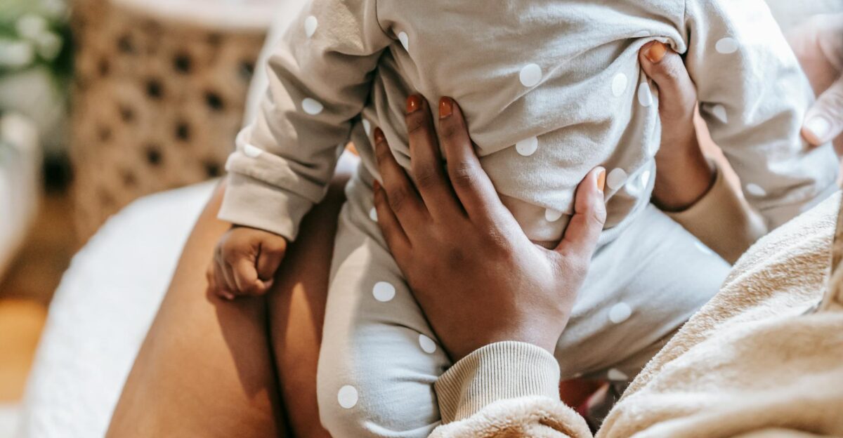 Crop unrecognizable ethnic mom interacting with little child in ornamental clothes in light house room