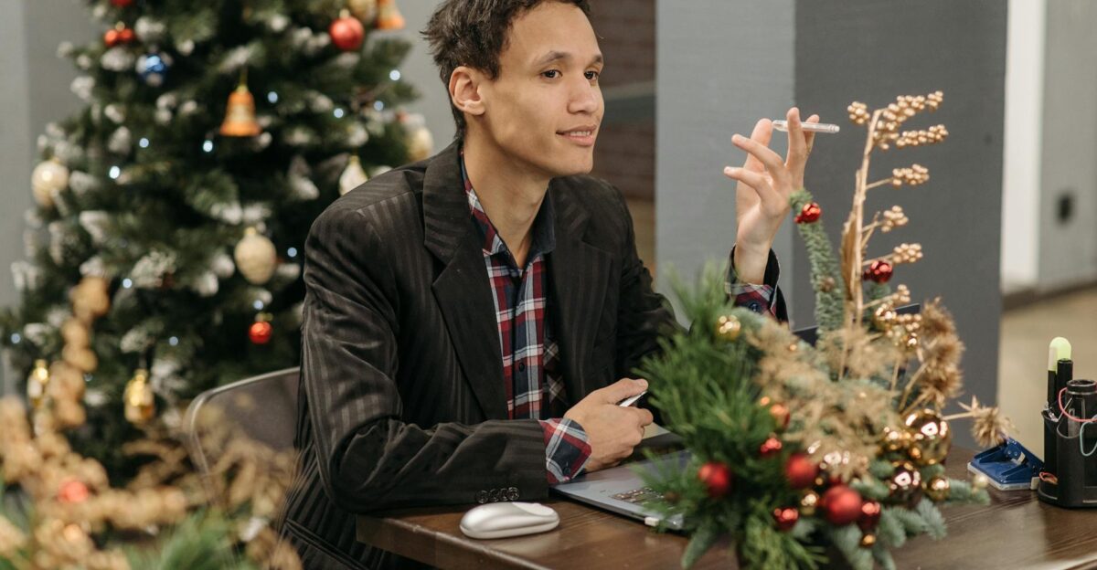 Man sitting at office desk surrounded by festive Christmas decorations and a tree