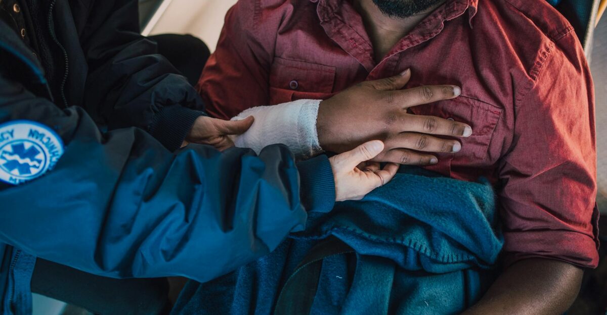 Paramedic assisting injured patient with arm bandaged in an emergency scenario